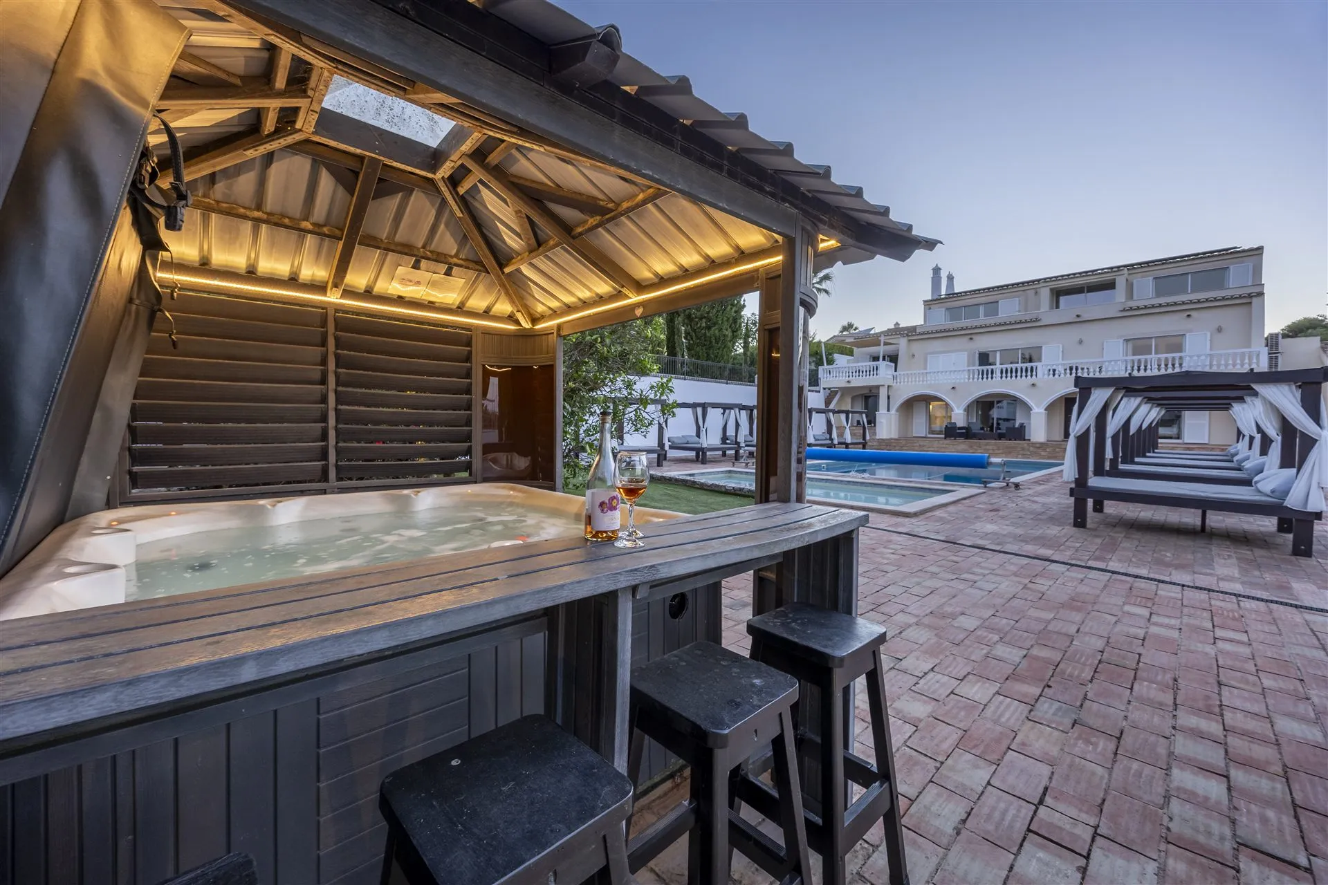 Hot tub bar gazebo beside the villa pool at dusk