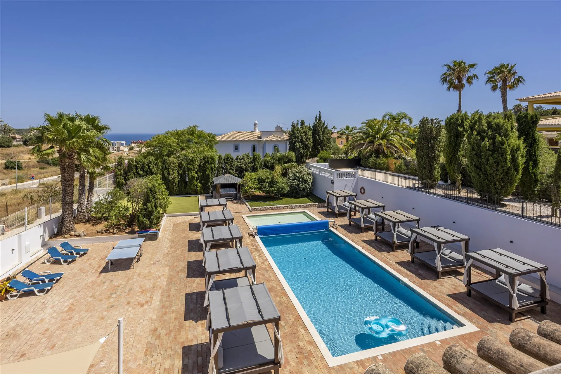 Aerial view of the Villa Lux Luz pool, day beds and gardens with the sea beyond